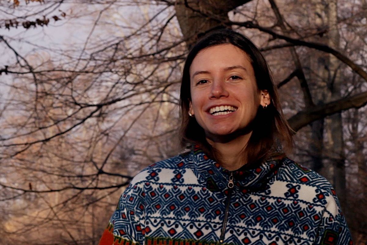 Portrait of a smiling young woman, trees on the background.