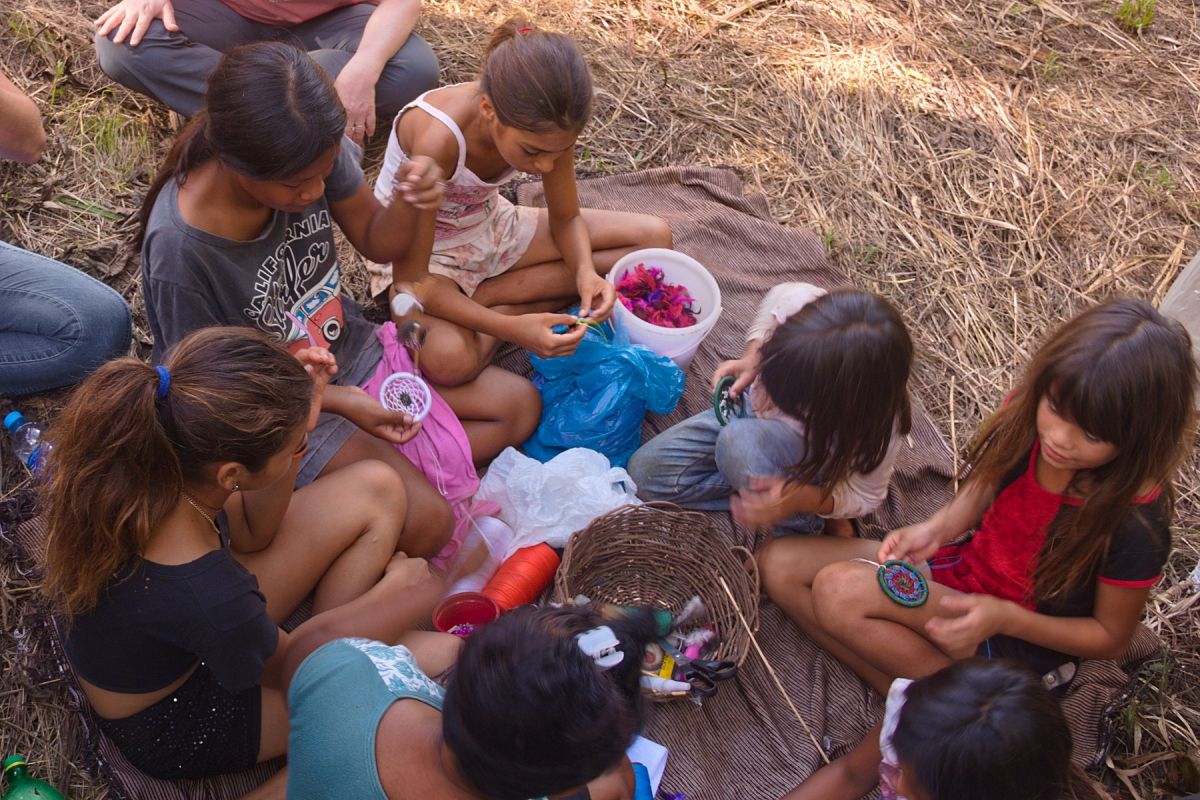 Guarani women producing dreamcatchers sitting on the ground