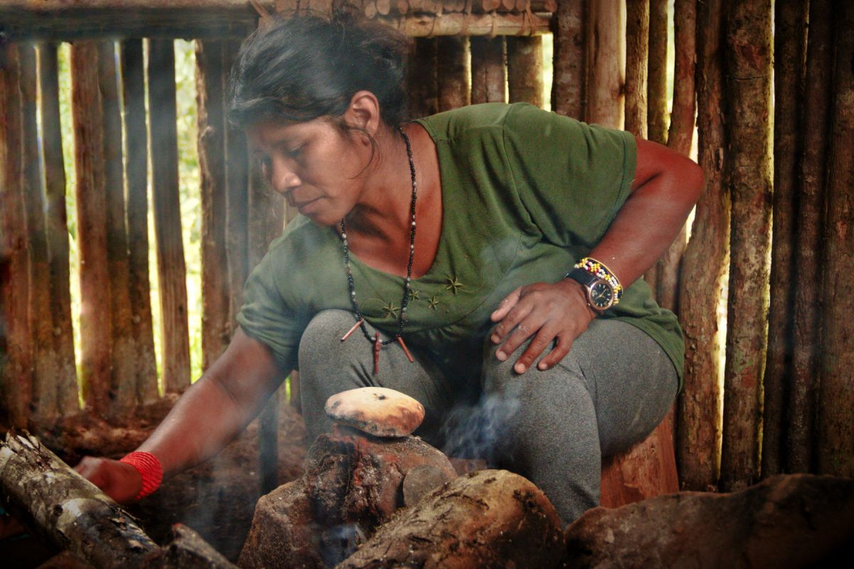 Guarani woman cooking on the fireplace in a hut.